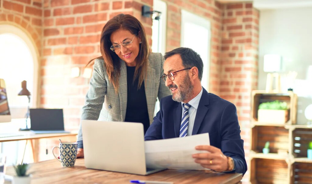 Two middle aged workers smiling while discussing